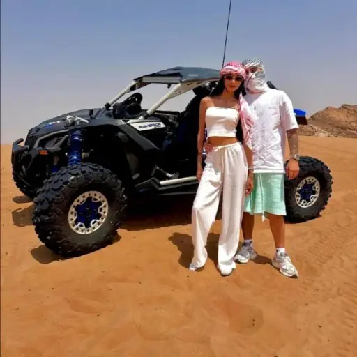 Couple in a black Can-Am X3 dune buggy mid-action on Dubai red dunes