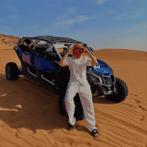 Family in a 4-seater Can-Am dune buggy, dust spray on Lahbab Desert Red Dunes dune crest
