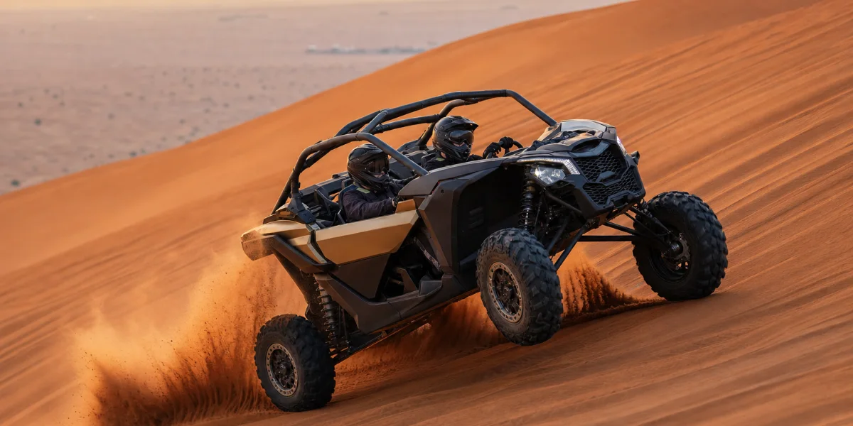 Can-Am X3 Turbo climbing a Lahbab dune at golden hour with both riders wearing helmets and visors down
