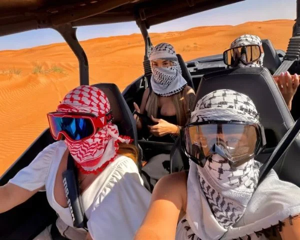 Close-up of a dune buggy rider gripping the roll cage in full helmet and harness during a self-drive tour in Dubai