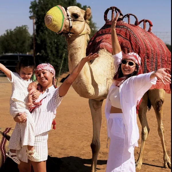 EVENING CAMEL + SAFARI Guests posing with a camel before an evening desert safari in Lahbab Dubai