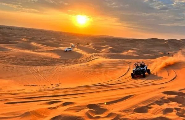 Dune buggy racing across Lahbab Desert Red Dunes at golden hour sunset — Dune Buggy Dubai Rides base camp, southeast Dubai