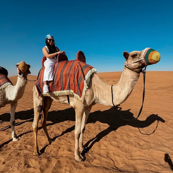 Guest riding a camel through Lahbab red dunes during a morning camel ride in Dubai