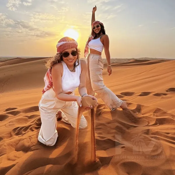 Guests sitting on Lahbab red dunes during a morning desert safari in Dubai