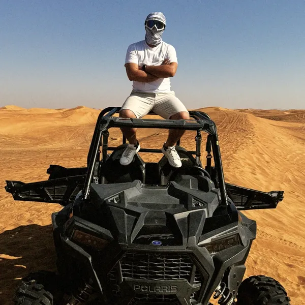 RED DUNES + DUNE BUGGY Guest standing on a dune buggy in Lahbab red dunes during a desert safari combo