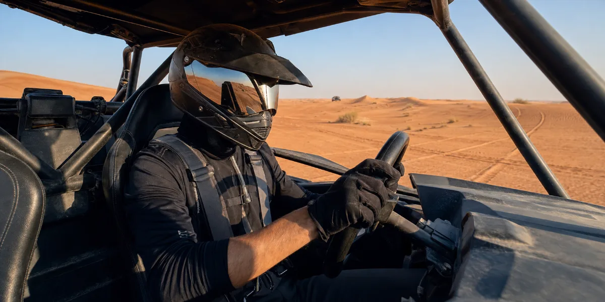 Helmeted self-drive dune buggy driver inside a roll cage in Lahbab Desert Dubai