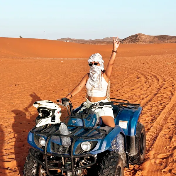STANDARD + QUAD BIKE Rider sitting on a quad bike in Lahbab red dunes before a standard desert safari combo