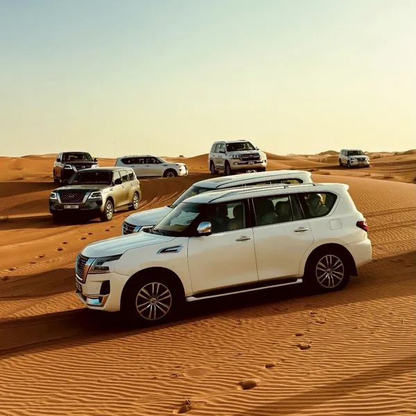STANDARD EVENING SAFARI White Land Cruiser convoy parked on Lahbab red dunes for a standard evening desert safari