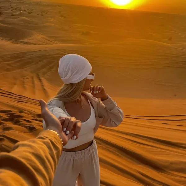 SUNSET DESERT SAFARI Guest posing on Lahbab red dunes during a sunset desert safari in Dubai